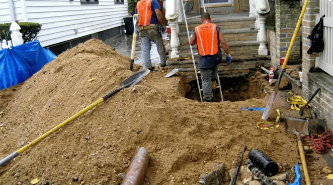 Contractors performing foundation protection and exterior drainage excavation near residential home steps in Mesa, AZ