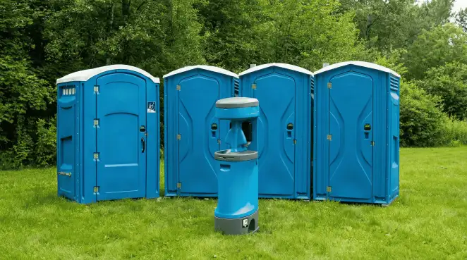 Four blue portable toilets and a matching hand washing station on grass near trees, a common sight at local outdoor events in Mesa, AZ