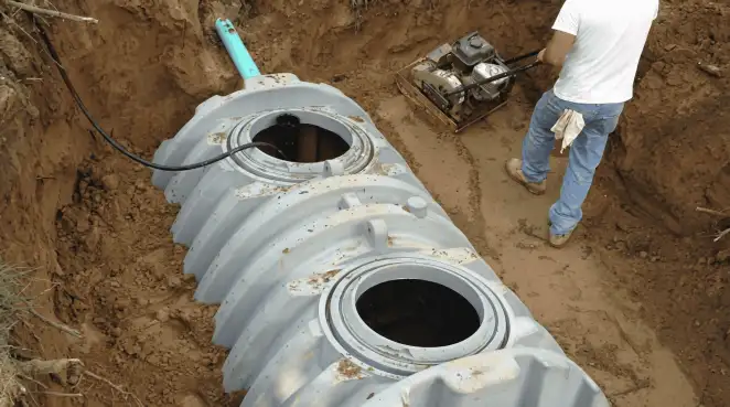 Septic tank installation showing a technician compacting soil around a new poly septic tank in an excavation pit in Mesa, AZ
